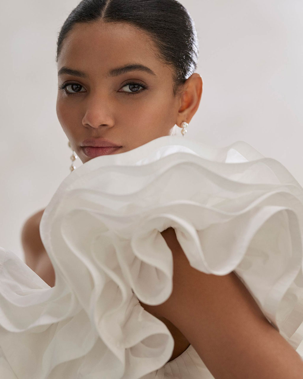Portraitaufnahme einer eleganten jungen Frau mit dunklem Teint und einem Rosa Clara Brautkleid