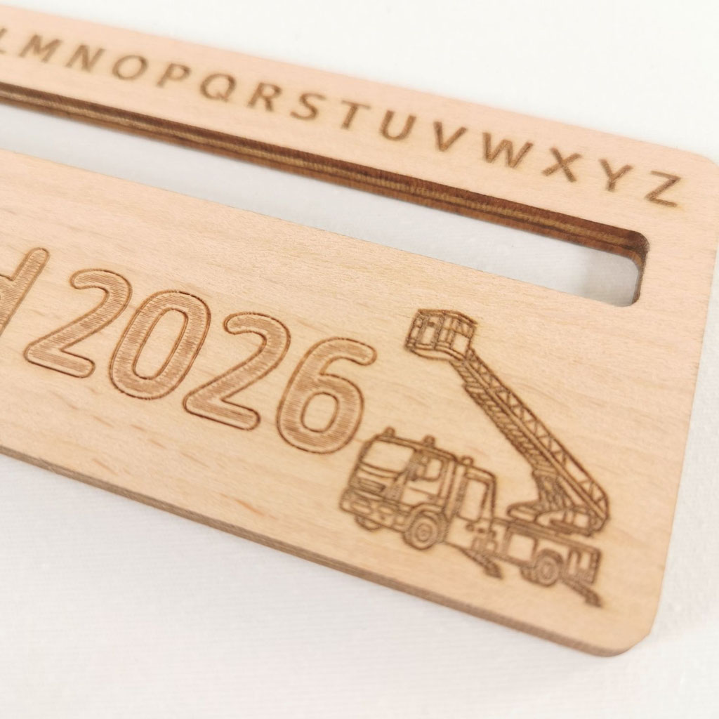 Detailansicht eines personalisierten Leselineals aus Holz mit graviertem Feuerwehr-Motiv, Drehleiter und Jahreszahl 2026