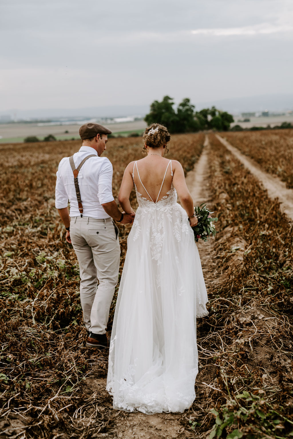 Hochzeitsfotograf Mainz - Brautpaar läuft Hand in Hand einen Feldweg entlang