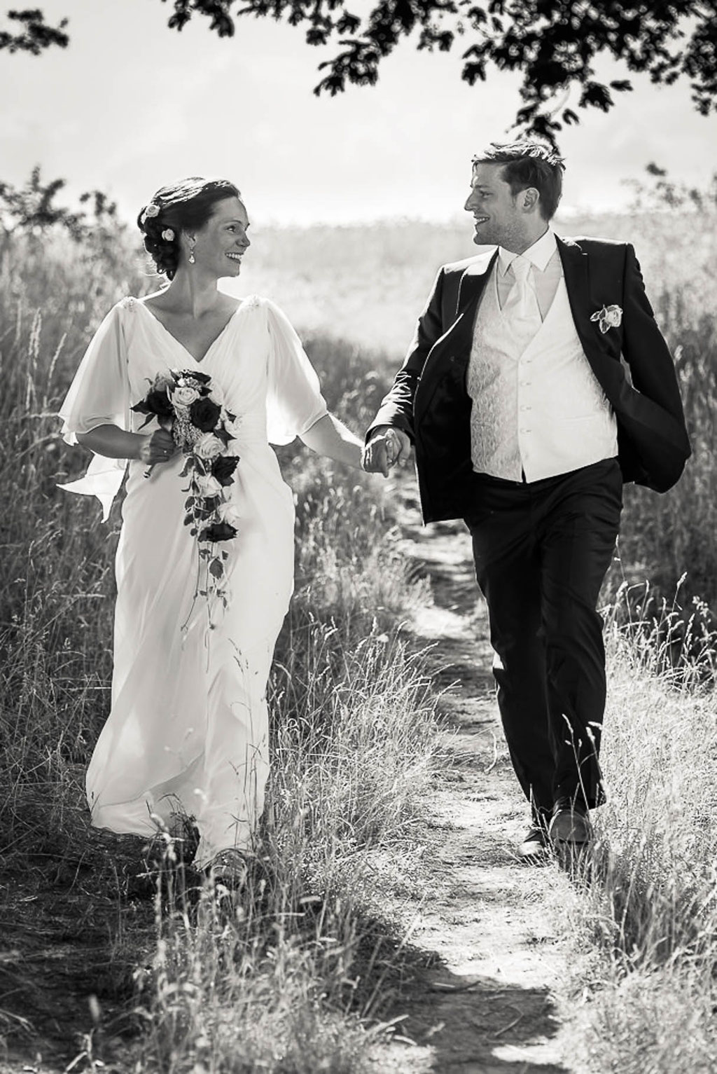 Hochzeitsfotograf Mainz - Brautpaar rennt Hand in Hand einen Feldweg entlang