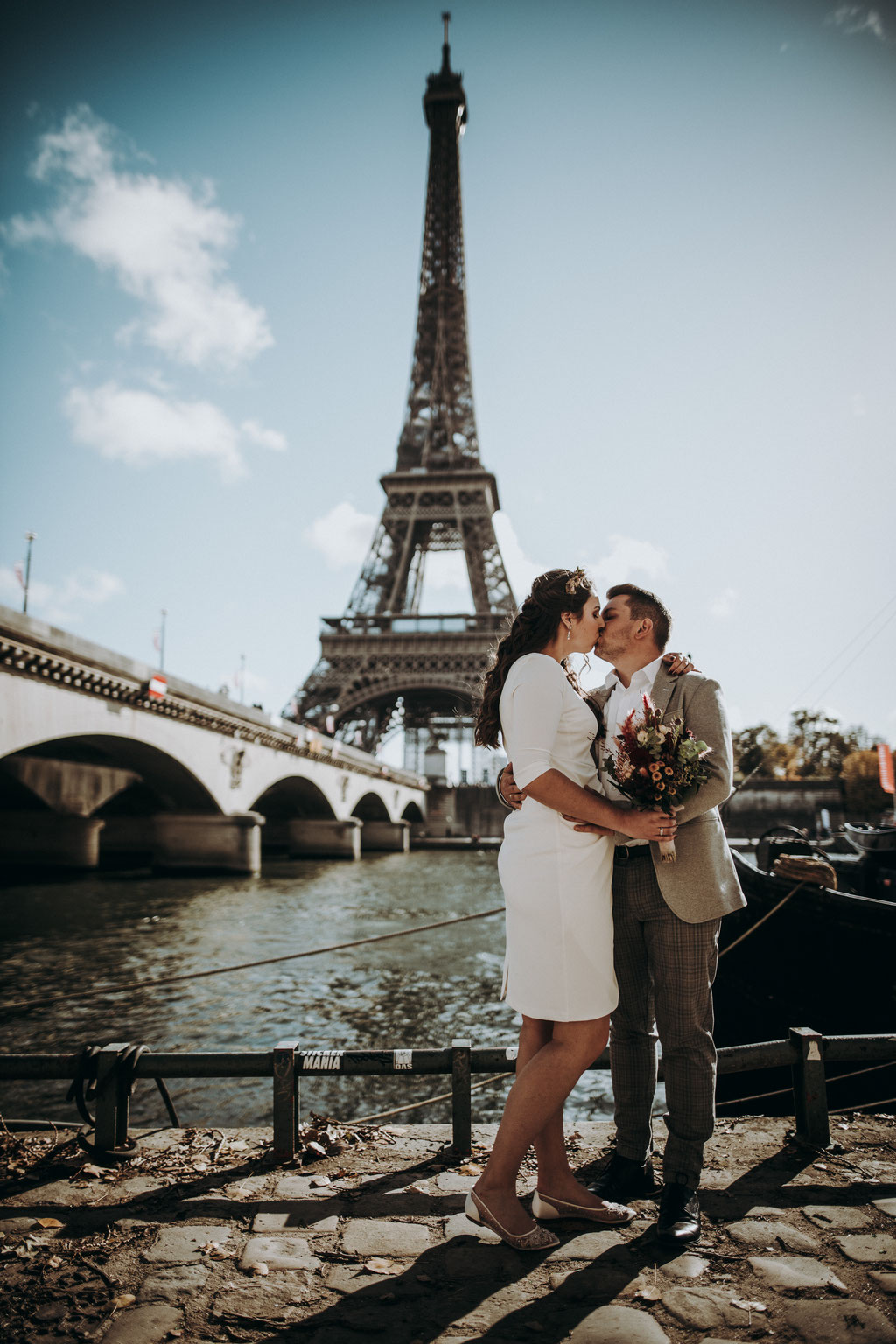 Destination wedding in Paris at the Eiffeltower - Destination wedding photographer - Brautpaar steht am Seineufer, im Hintergrund der Eiffelturm