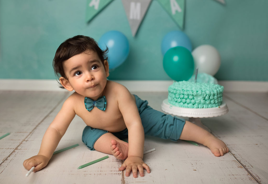 Fröhlicher Junge beim Smash-the-Cake-Shooting vor türkisem Hintergrund mit Luftballons im Studio Hamburg