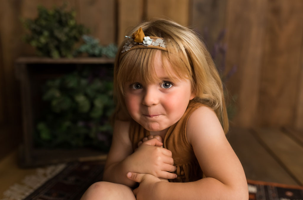 Kleines Mädchen posiert in einer gemütlichen, rustikalen Holzkulisse im Fotostudio Hamburg-Rahlstedt