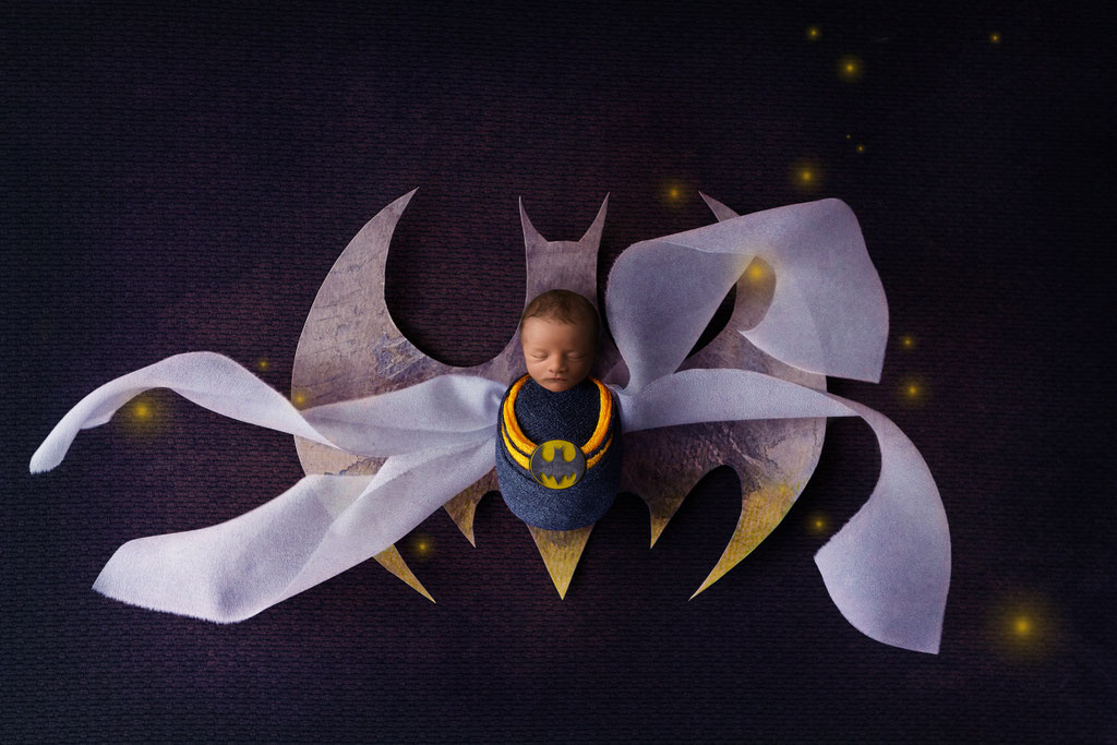 Süßes Batman Babyfoto im gelben Look in einer Holzschale auf grünem digitalem Hintergrund
