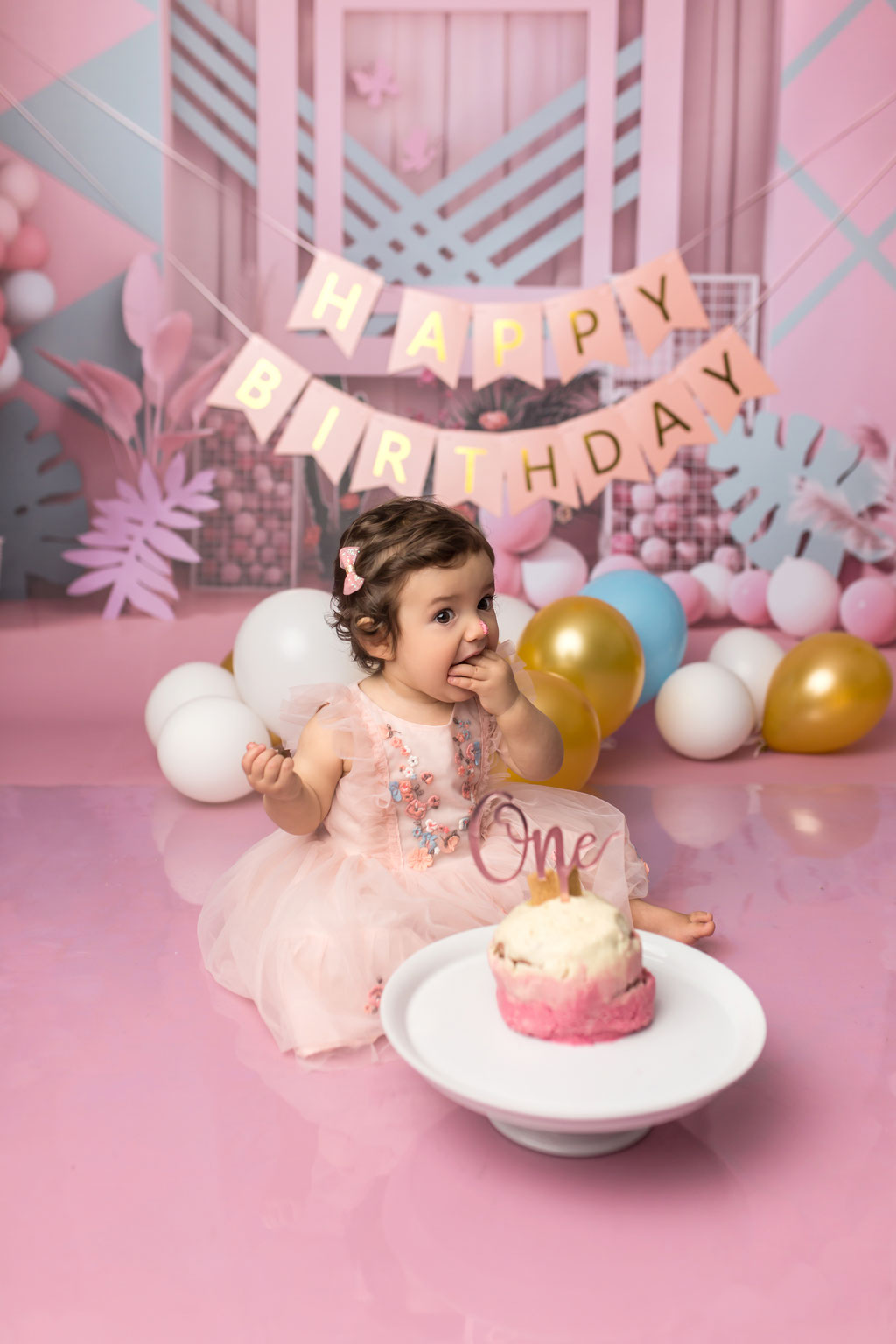 Einjähriges Mädchen feiert Cake Smash vor rosa Hintergrund mit vielen bunten Ballons in Hamburg-Rahlstedt