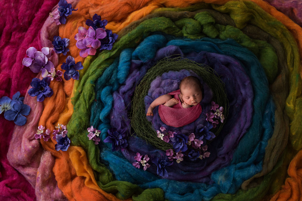 Kreative Neugeborenenfotografie mit digitalem Hintergrund in Regenbogenfarben und rosa gepucktem Baby Hamburg