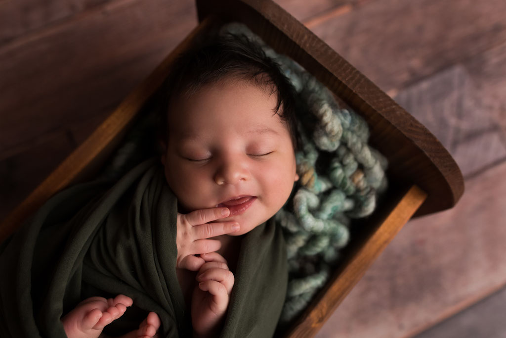 Baby in einem Holzbattchen lacht im Schlaf 