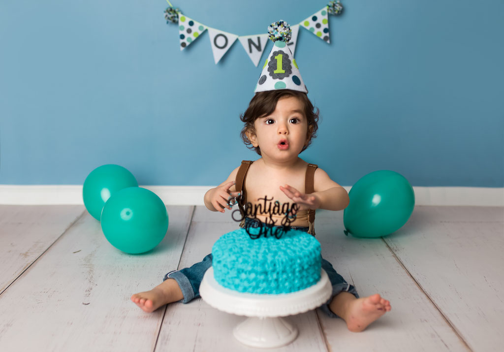 Fröhlicher Junge feiert ersten Geburtstag vor blauem Hintergrund im Fotostudio Hamburg