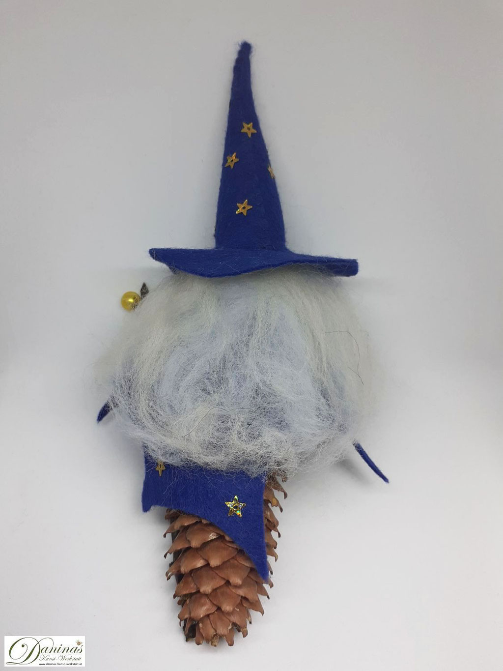 Zauberer Rückseite. Handgefertigte Figur aus Fichtenzapfen, mit weißen Haaren und langem Bart aus Wolle, blauem Zauberhut und Zaubermantel, magischem Zauberstab