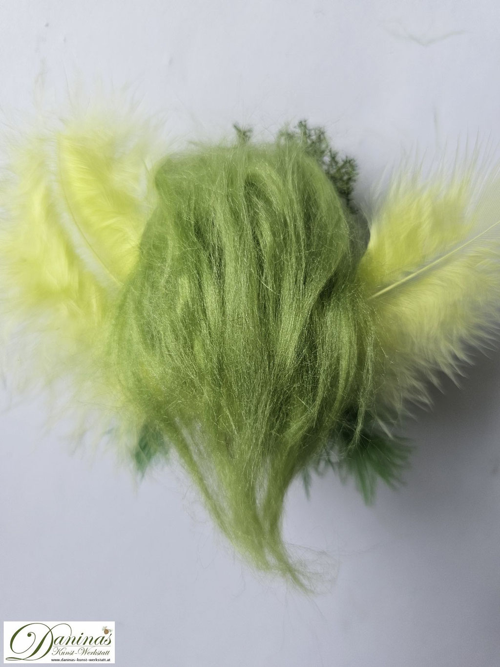 Waldfee Figur Tilia Rückseite, handgefertigt aus Fichtenzapfen, mit lindgrünen Haaren aus Wolle, gelb-grünen Federnflügeln, grünen Blättern aus Filz. Irisches Moos und Ziersteine als Haarschmuck