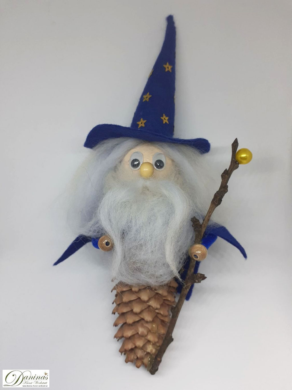 Zauberer Merlin jun. Handgefertigte Märchenfigur aus Fichtenzapfen, mit weißen Haaren und langem Bart aus Wolle, blauem Zauberhut und Zaubermantel, magischem Zauberstab