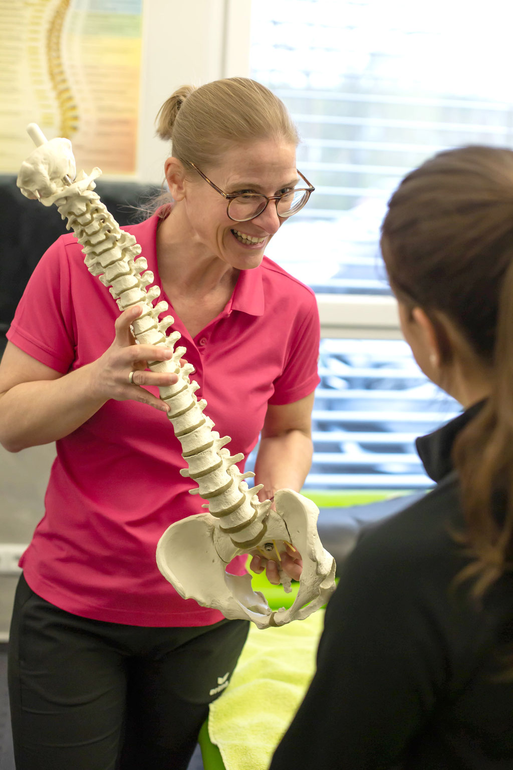 Therapeutin erklärt einer Patientin die Wirbelsäule am Modell