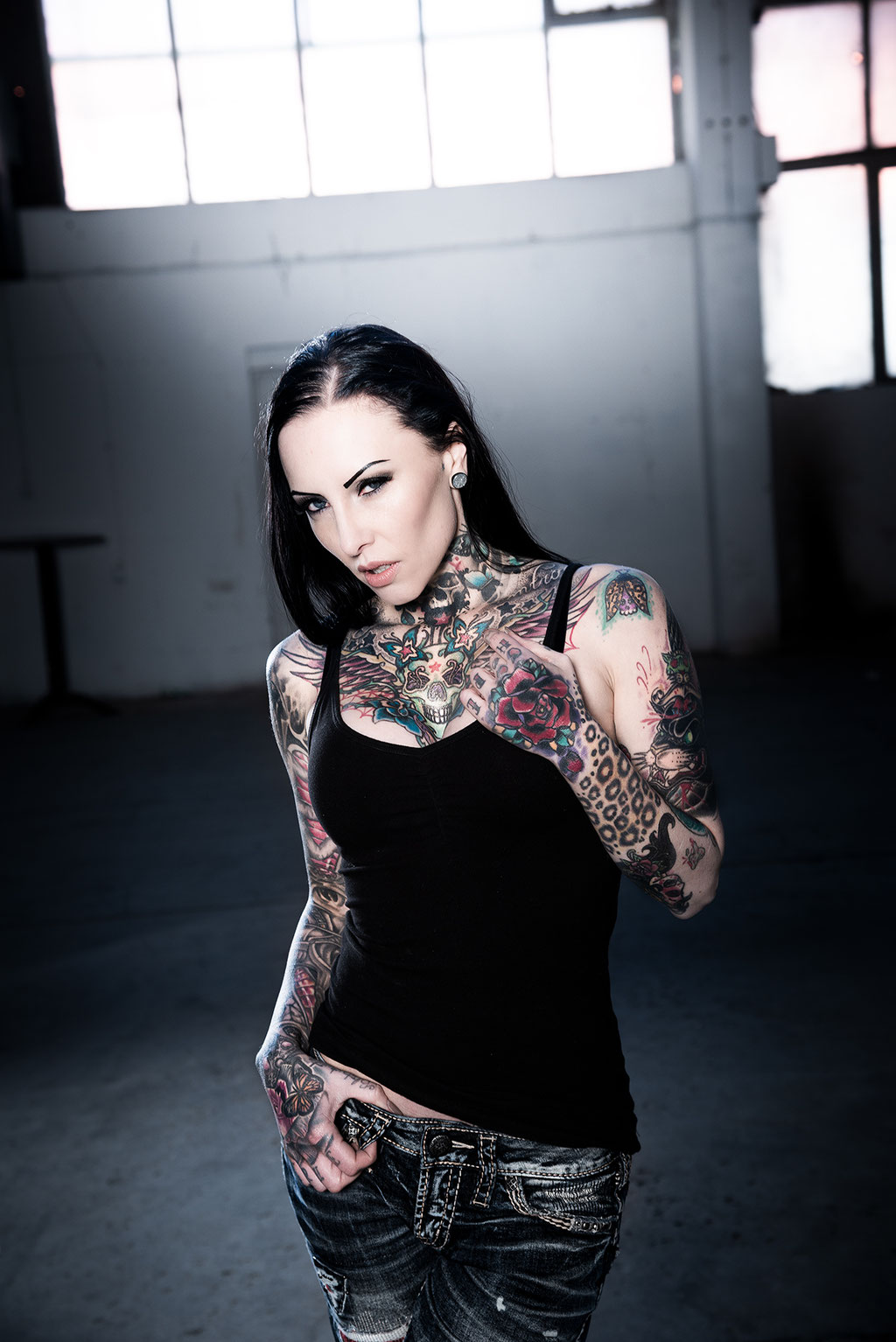 Tattoo model Makani Terror with jeans and shirt in an old building