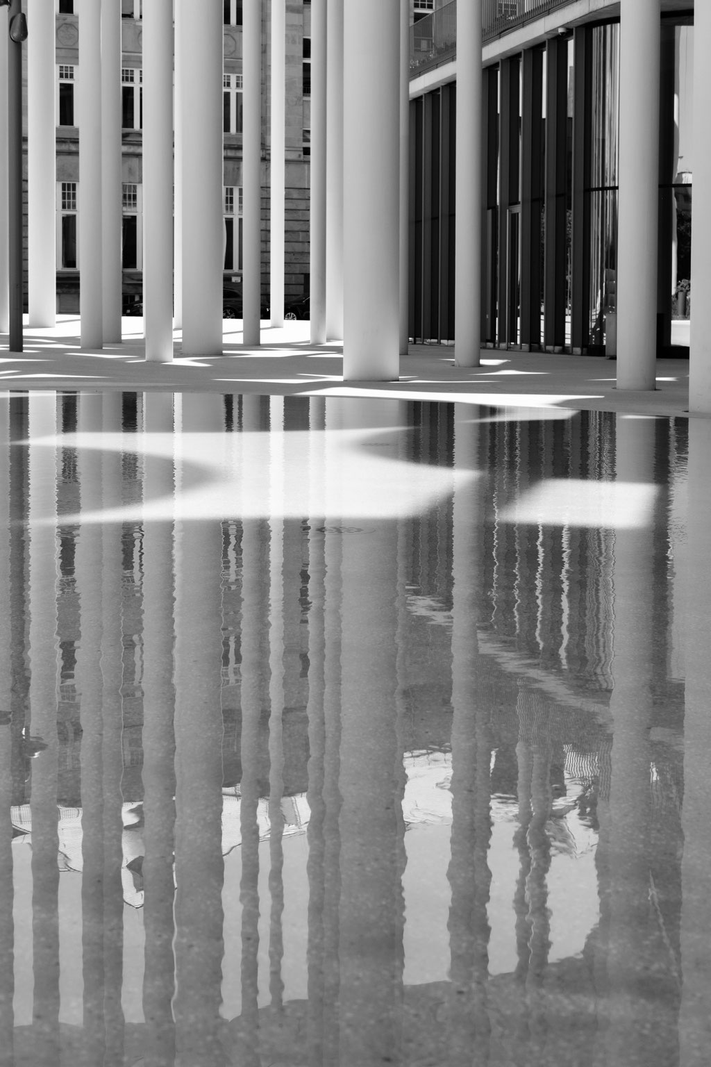 Spiegelung großer Säulen vor Architektur.