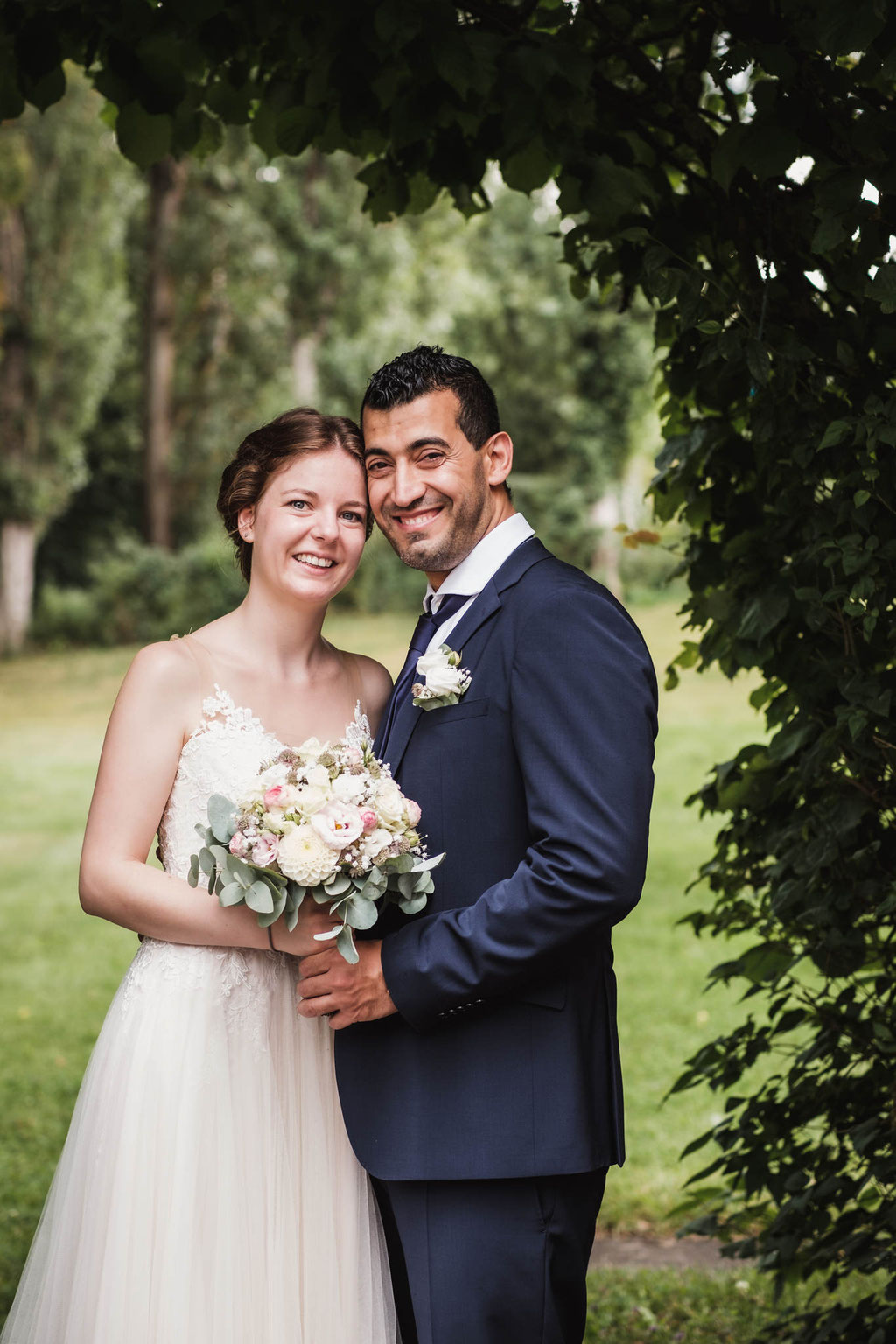 Hochzeitsfotografie des Brautpaares in grüner Umgebung.