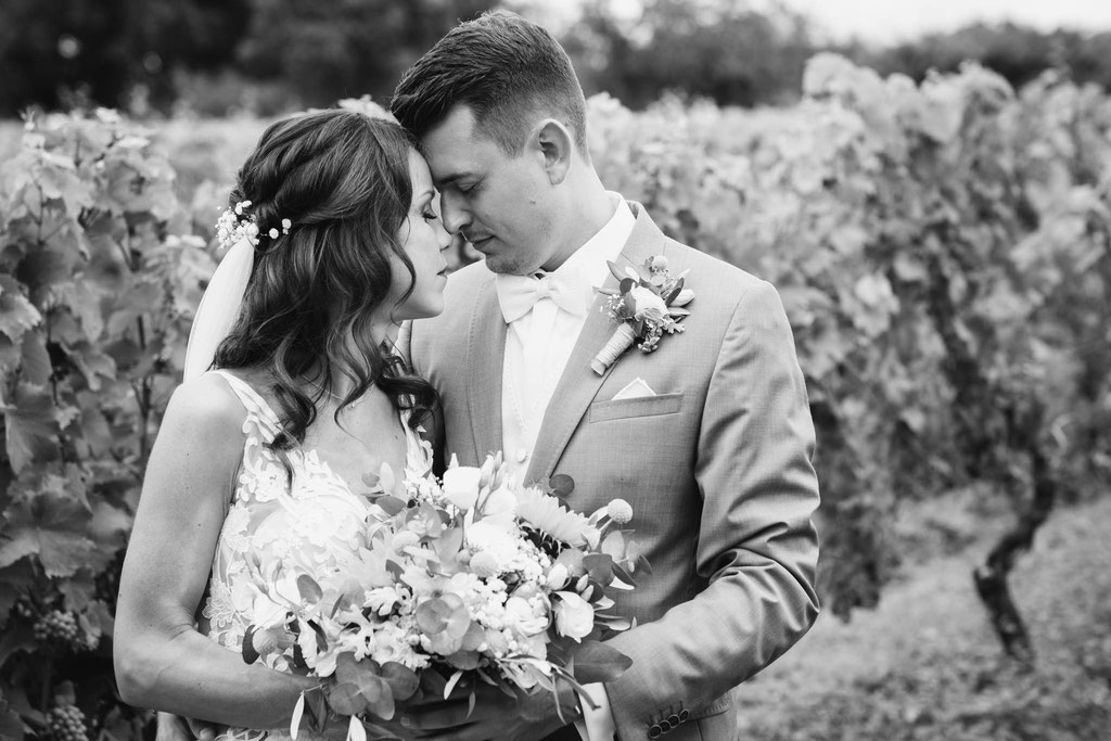 Hochzeitsfotografie des Brautpaares in schwarz weiß vor Weinbergen.