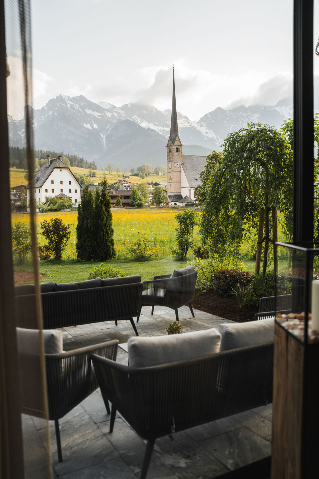 The terrace of the Hochkönigin Wellness Hotel in Maria Alm, Salzburg, with a view of the church and the mountain panorama