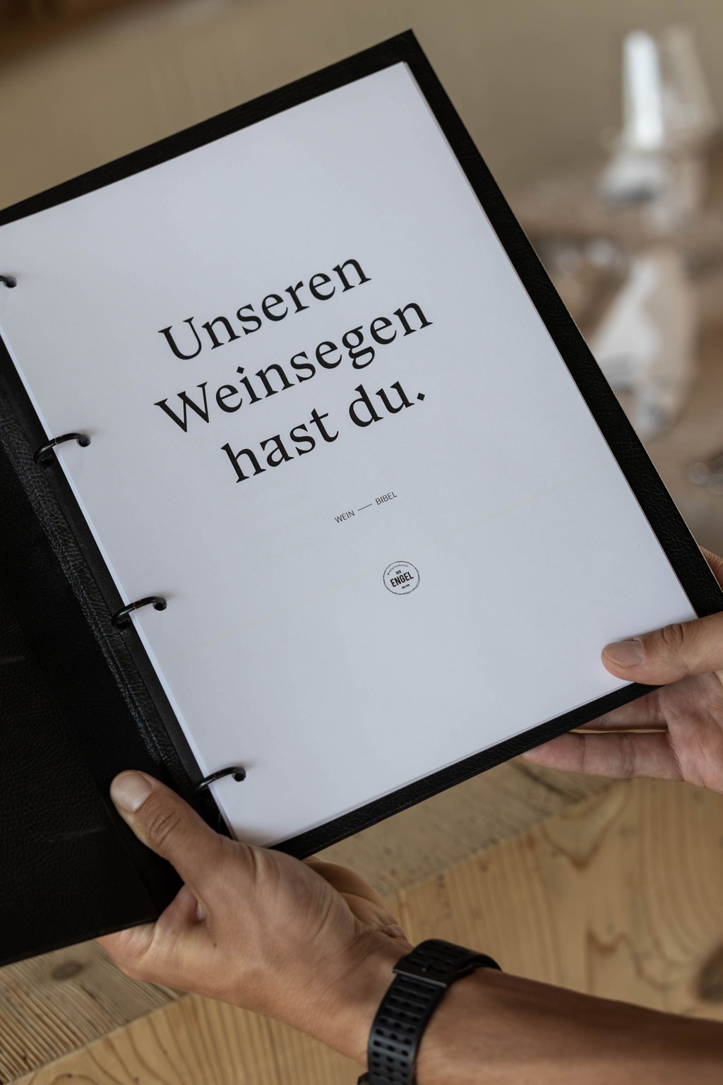 Geöffnete Weinkarte im Restaurant des DER ENGEL im Tannheimertal mit der humorvollen Botschaft „Unseren Weinsegen hast du.“ Die stilvolle Präsentation unterstreicht die gelebte Genusskultur und lädt dazu ein, ausgewählte Weine in besonderem Ambiente zu en