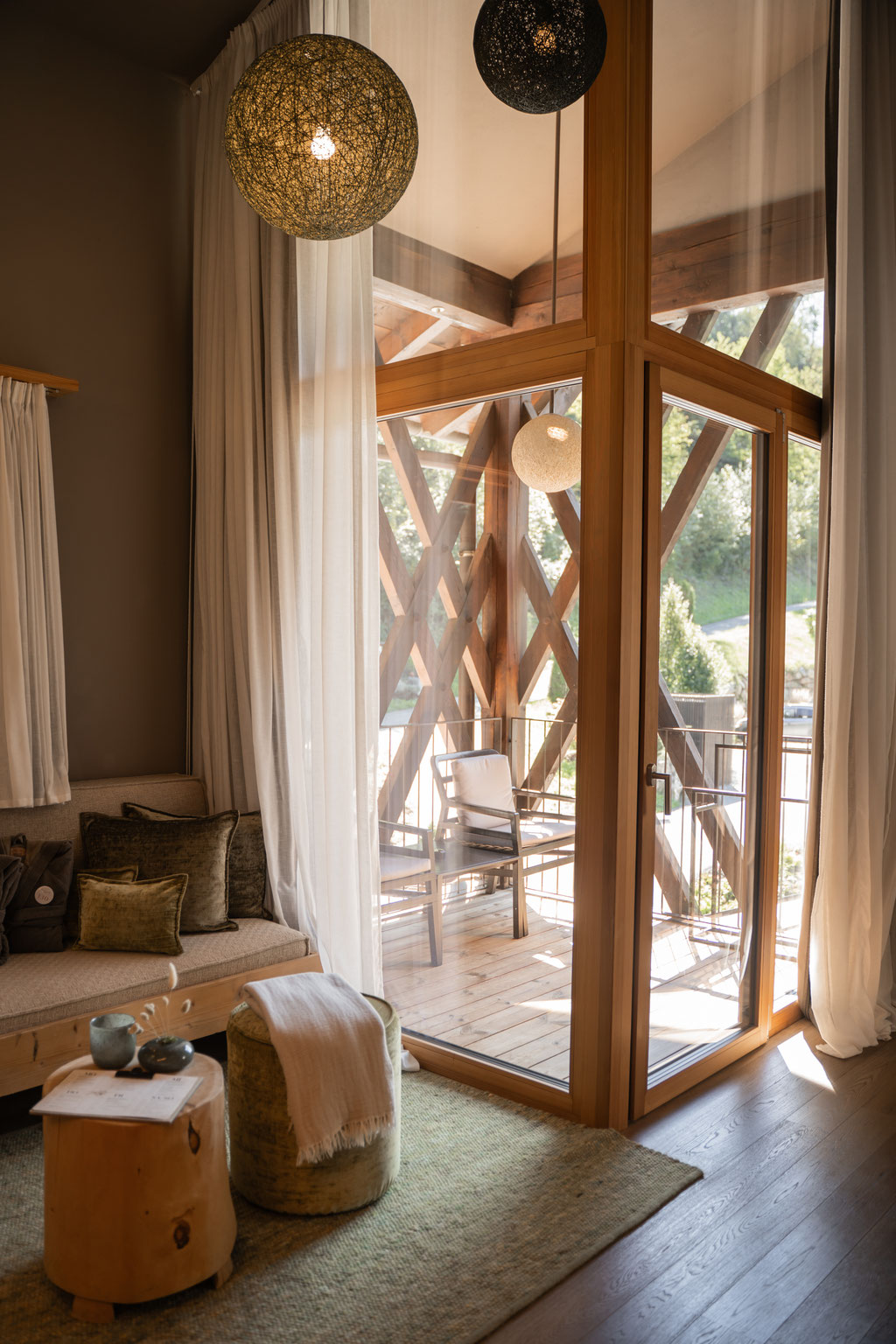 Heller Wohnbereich im Apfelhotel mit hohen Glasfronten, natürlichen Materialien und gemütlichem Balkonzugang.