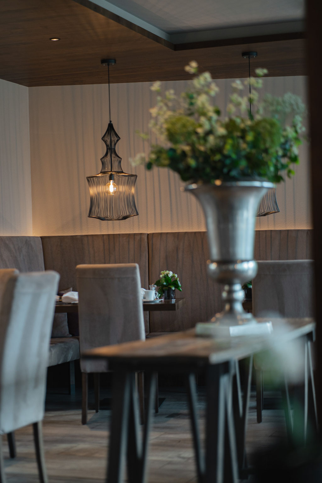 The stylishly furnished restaurant and breakfast area at the Hotel Mair am Ort Living in Partschins near Merano in South Tyrol, featuring elegant seating, decorative floral arrangements and a modern lighting scheme, all set in a cosy atmosphere.