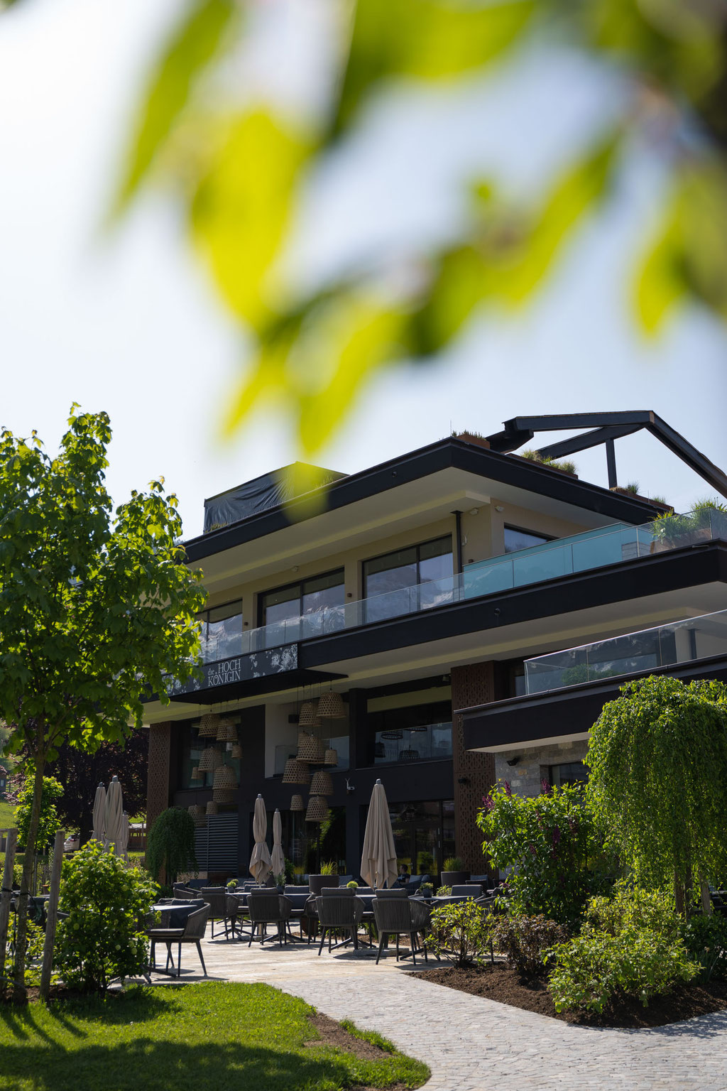 Exterior view of the Hochkönigin Wellness Hotel in Maria Alm, Salzburg, with a sun terrace and garden