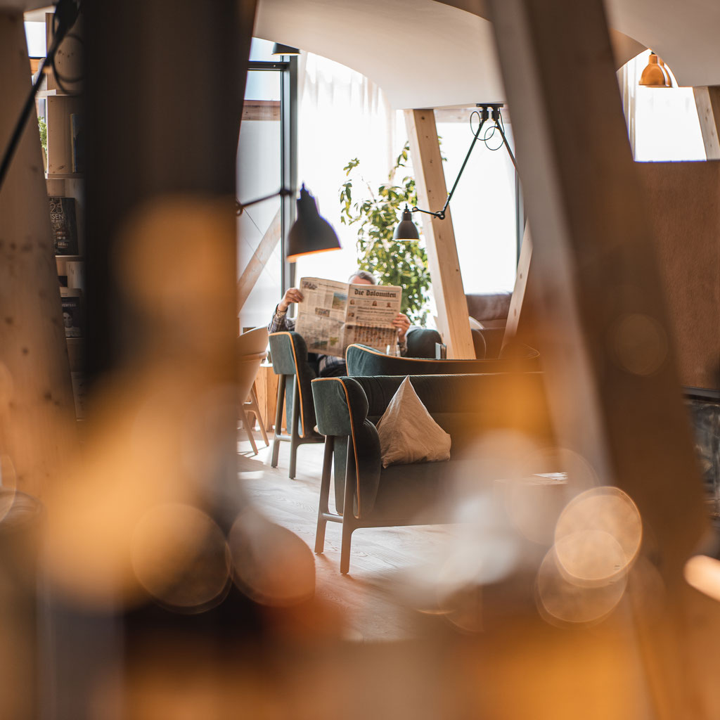 A cosy lounge area at the Garberhof, with warm lighting, wooden features and a guest relaxing with a newspaper.
