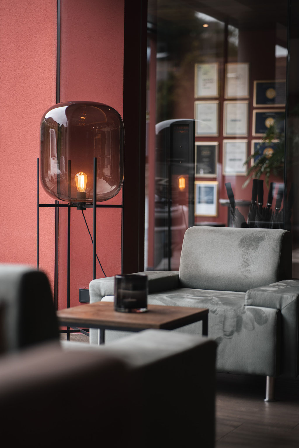 A cosy seating area with an armchair, side table and stylish designer lamp at the Hotel Mair am Ort Living in Partschins near Merano in South Tyrol. The warm lighting and modern ambience invite you to linger and relax.