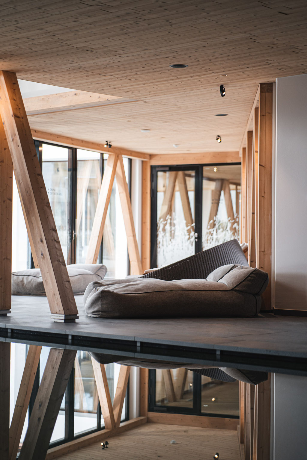 A comfortable lounger by the indoor pool in a modern wellness area featuring wooden décor.