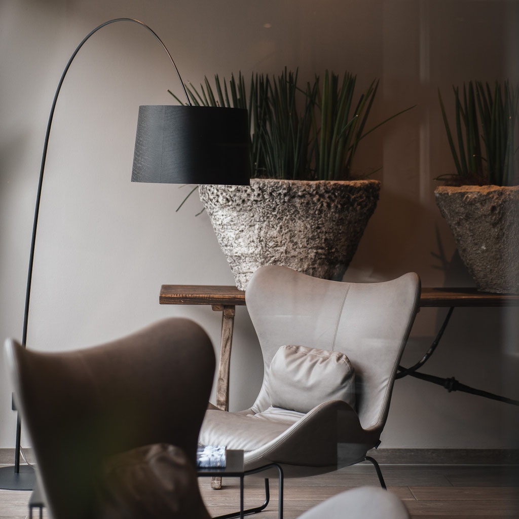 A stylishly furnished lounge area with comfortable armchairs, designer lighting and decorative planters at the Hotel Mair am Ort Living in Partschins near Merano in South Tyrol.