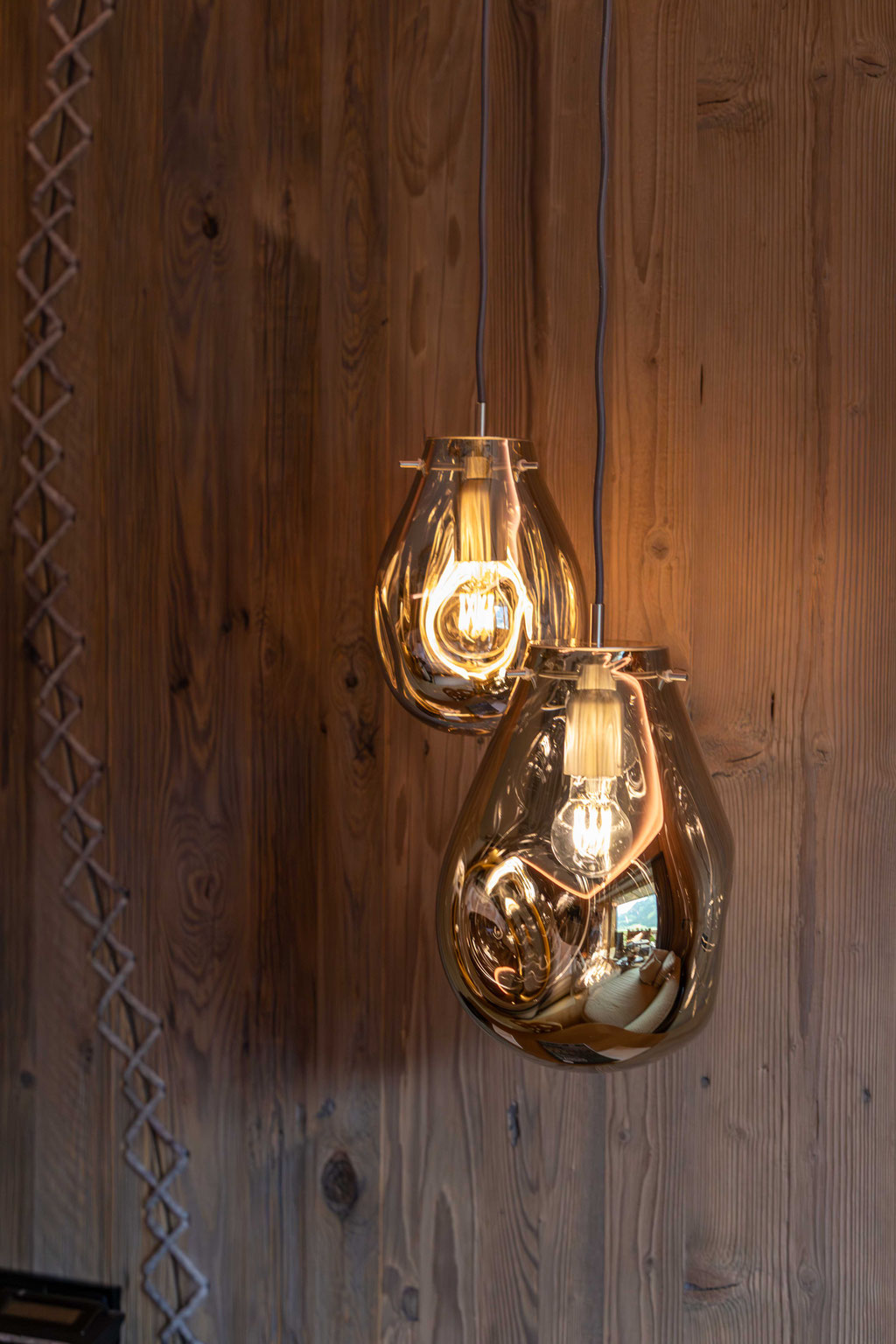 Zwei elegante Pendelleuchten mit warmem Licht setzen stilvolle Akzente im Zimmer des DER ENGEL im Tannheimertal. Die Kombination aus edlem Glas, natürlichem Holz und hochwertigem Design schafft eine behagliche Atmosphäre zum Ankommen und Entspannen.