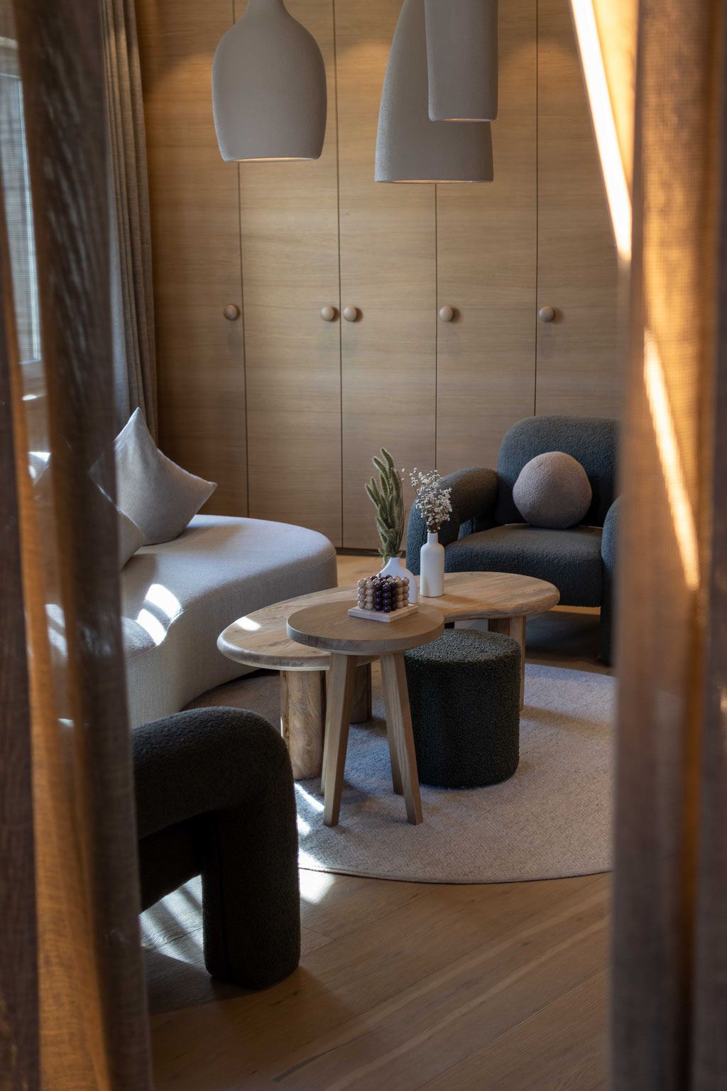 Stilvoll eingerichteter Wohnbereich mit gemütlichen Sesseln, Holztischen und natürlicher Einrichtung im Boutiquehotel PETRUS in Reischach-Bruneck • Südtirol, der zum Entspannen und Verweilen einlädt.