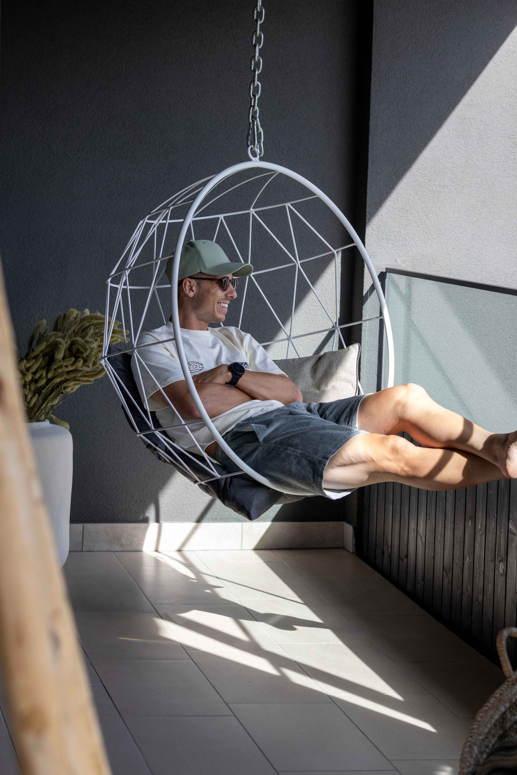 Gast entspannt in einem modernen Hängesessel auf der Terrasse des Boutiquehotel PETRUS in Reischach-Bruneck • Südtirol und genießt die ruhige, sonnige Wohlfühlatmosphäre.