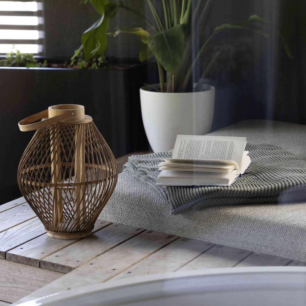 Gemütlicher Ruhebereich mit Liege, offenem Buch, weicher Decke und dekorativer Laterne im Boutiquehotel PETRUS in Reischach-Bruneck • Südtirol, ideal zum Lesen und Entspannen.