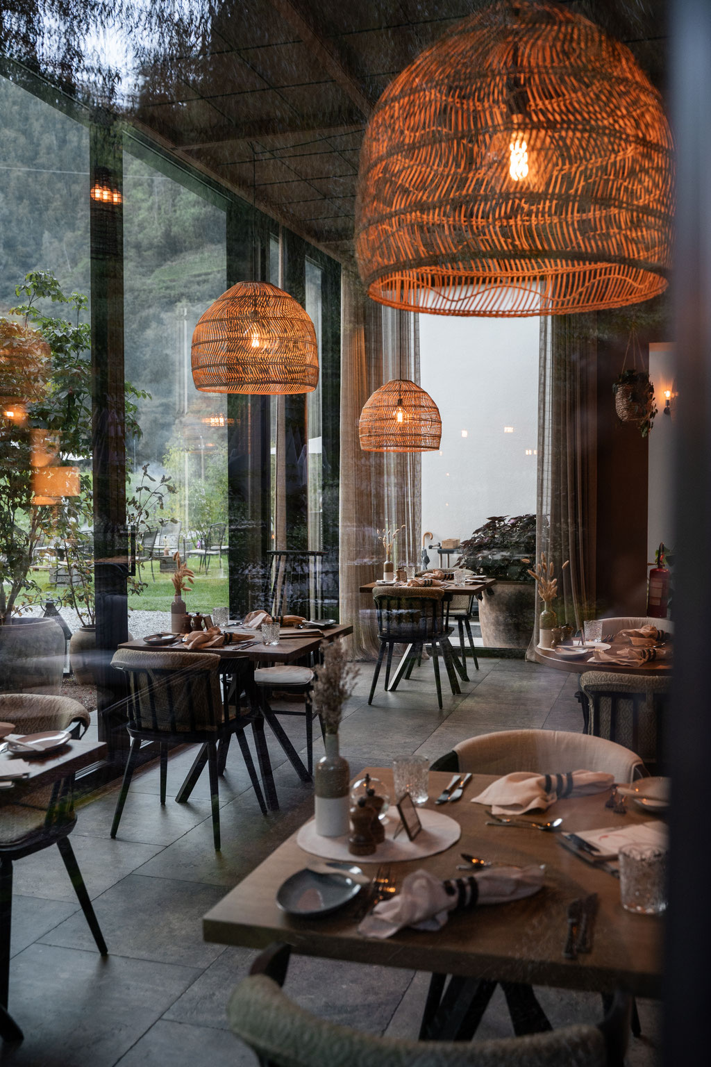 Modernes Restaurant im Apfelhotel mit stilvoll gedeckten Tischen, warmem Licht und großen Glasfronten zur Gartenlandschaft.