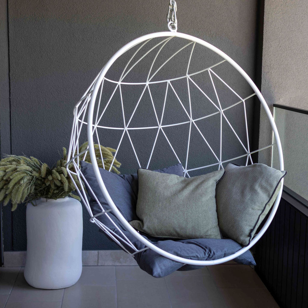 Moderner Hängesessel mit weichen Kissen auf einer Terrasse des Boutiquehotel PETRUS in Reischach-Bruneck • Südtirol, gestaltet als gemütlicher Rückzugsort zum Entspannen.