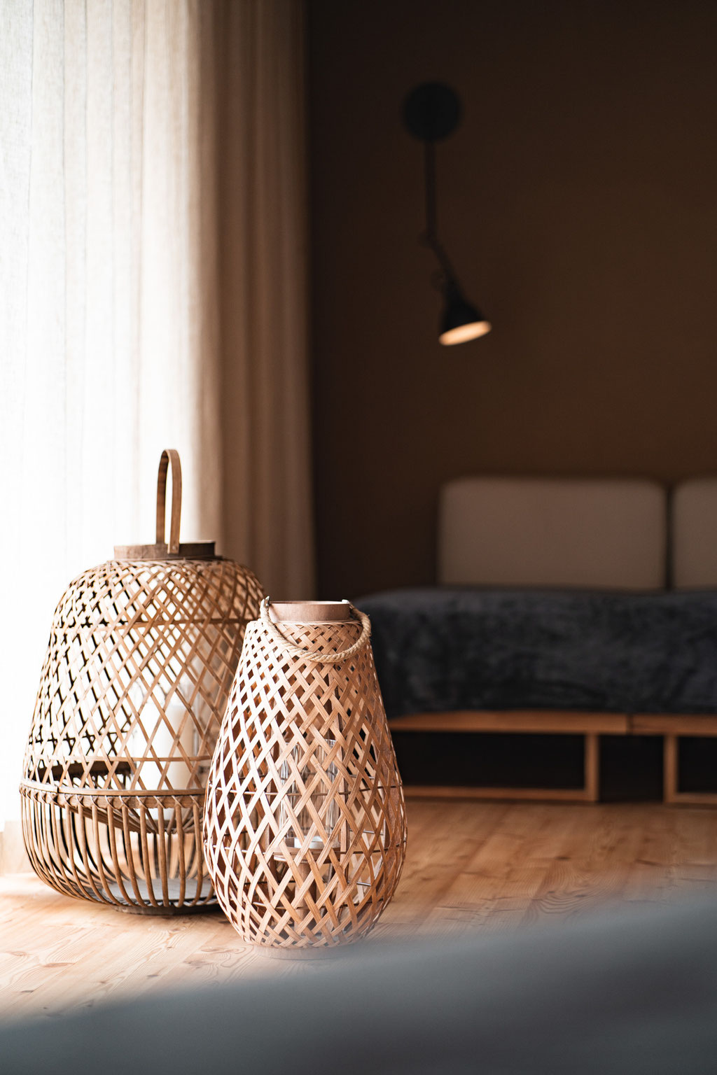Woven lanterns made from natural materials on a wooden floor in a cosy hotel room.