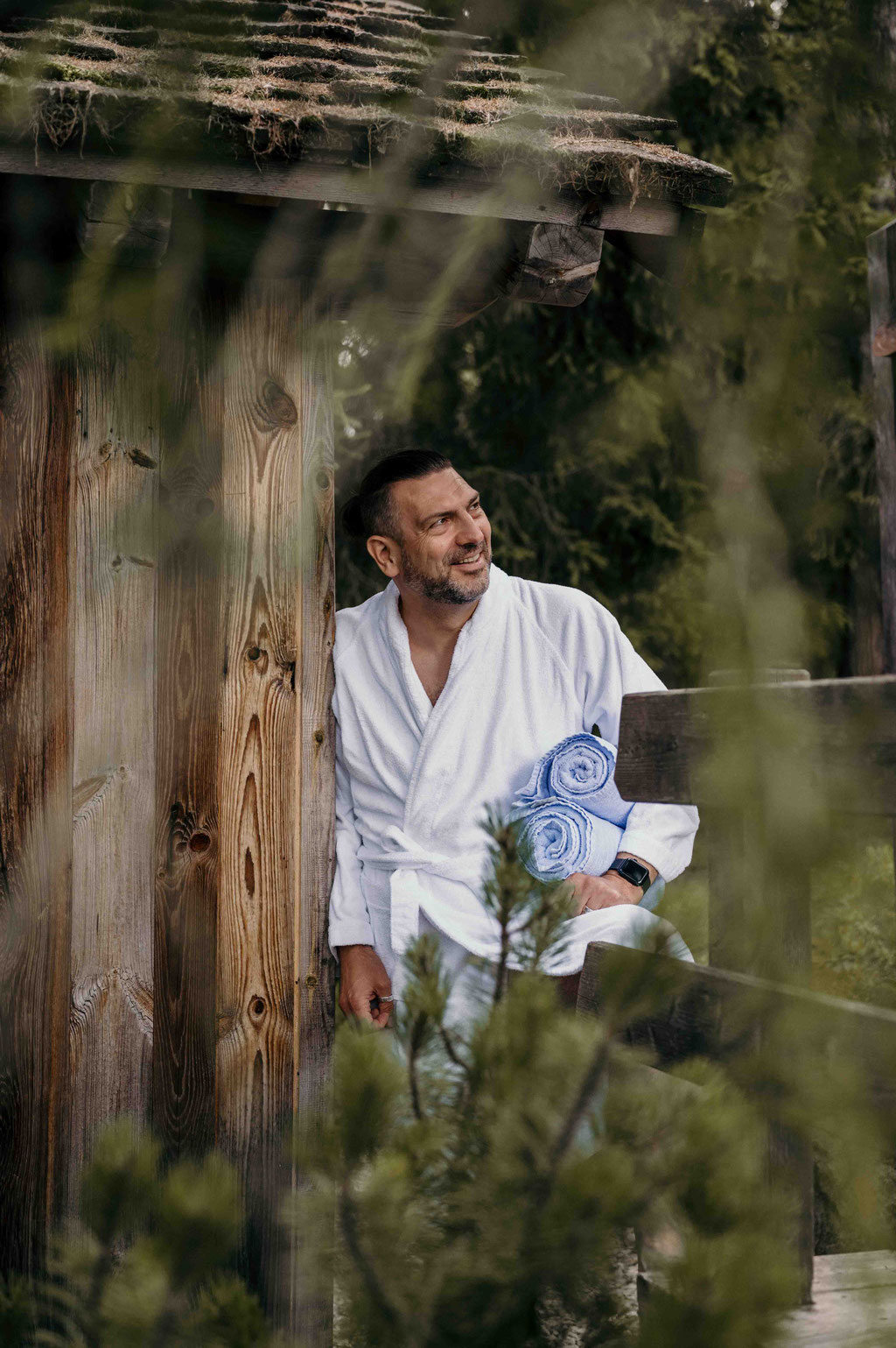 Man standing in front of the sauna cabin in the forest wellness area at Hotel Tann on the Ritten plateau in South Tyrol.