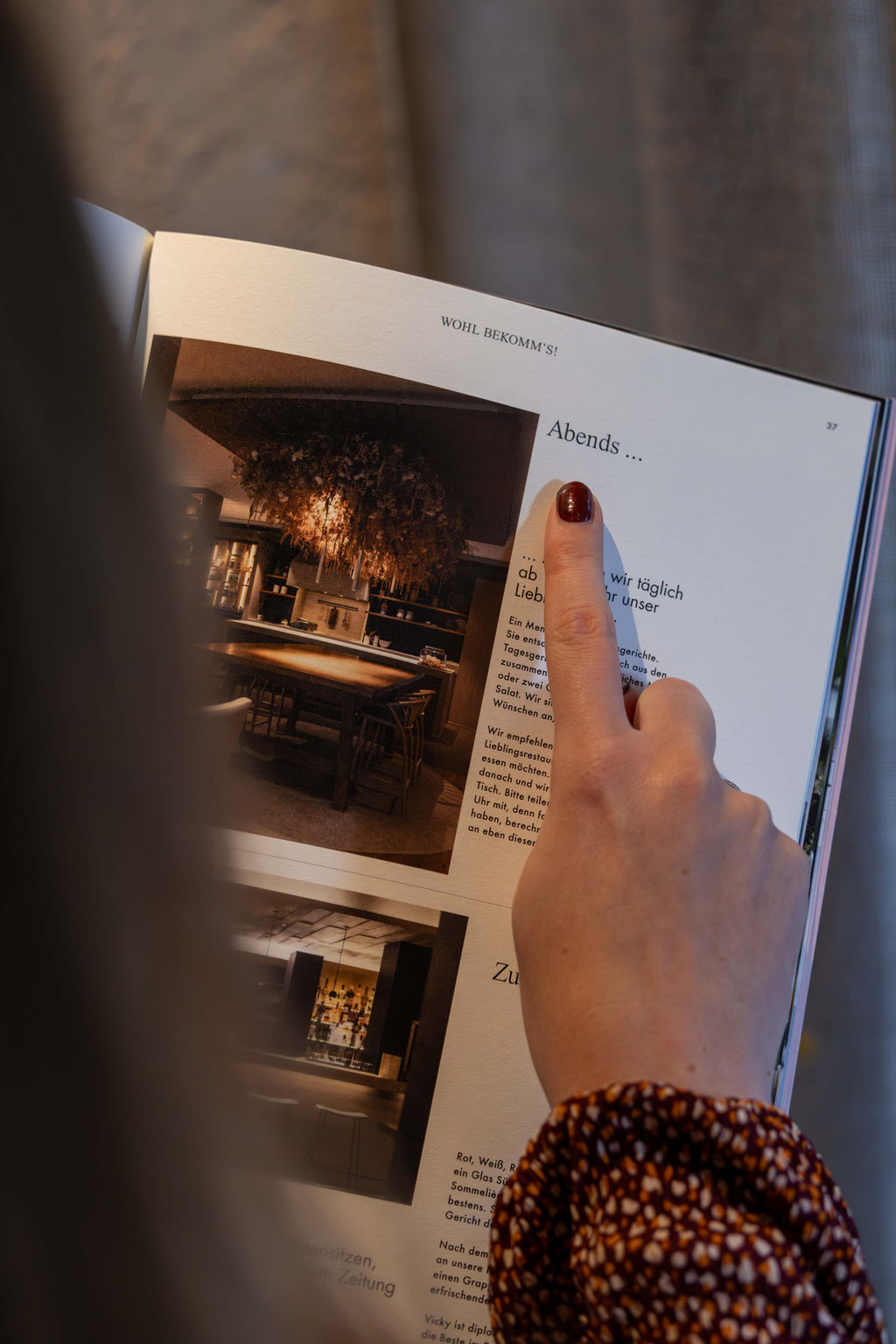 Gast blättert in der Hotelmappe des Boutiquehotel PETRUS in Reischach-Bruneck • Südtirol und informiert sich über Angebote, Kulinarik und Erlebnisse für den Aufenthalt.
