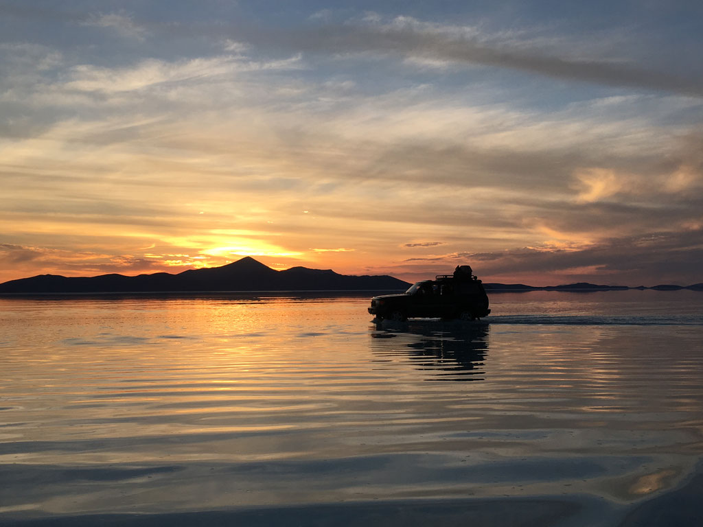 Bei Sonnenuntergang fahren wir durch die Wasserschicht auf dem Salzsee.