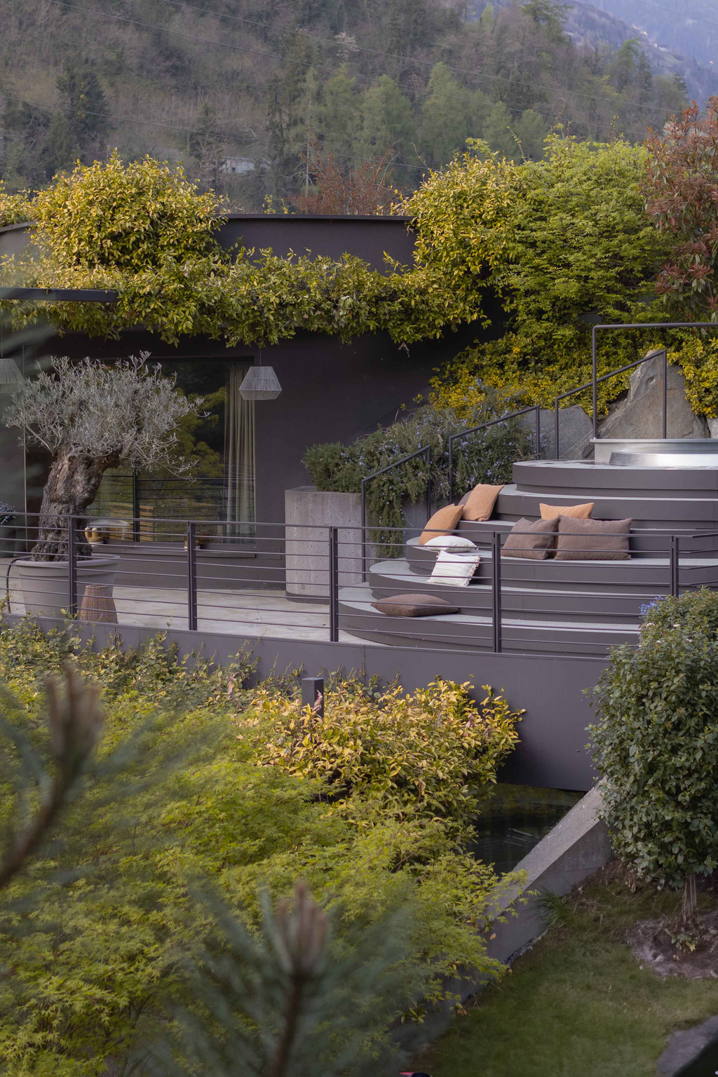 The terrace area of the Apfelhotel, featuring a modern outdoor design, comfortable seating and lush greenery on a hillside.