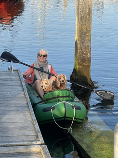 Zwei Cockerspaniel werden in einem Packraft an Land gerudert. Das Packraft kommt gerade am Steg an.