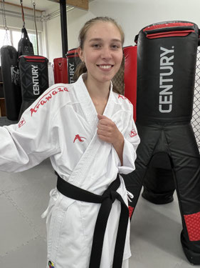 Auf dem Bild zu sehen ist Lea Sterk im Karate Anzug. Sie lacht und hat Spaß bei ihrer Arbeit.