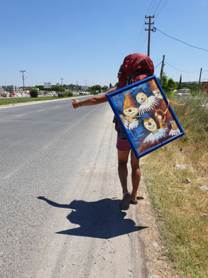 Viviane carrying one of the gifts attached to her bagpack, trying to hitchhike.