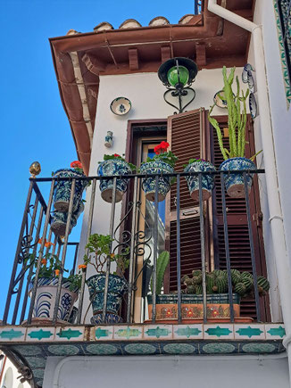 Hauswand mit Balkon, geschmückt mit Keramik, Blumentöpfen und Tellern