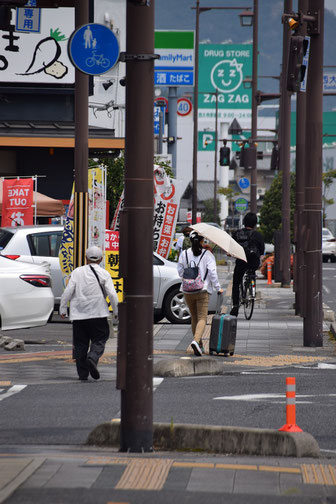 日傘をさして、スーツケース（後に追っかけてあるかれるKさん「日本のお父さん」のものかも知れません）ベトナム人のGさんがJR西大寺駅へ急ぐ姿です。教会から100㍍既に行かれてるかな、と思います。この景色を見ると、なんだか大きな町に見えるから不思議です。ちがいますよー（笑）