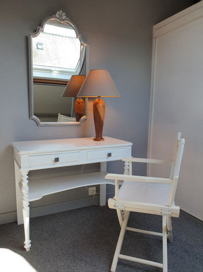 bureau blanc avec fauteuil et fleurs coquelicots, grand miroir argent, lampe sur pied violette
