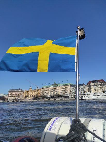 Eine schwedische Flagge eines Bootes vor einer Stockholmer Häuserkulisse