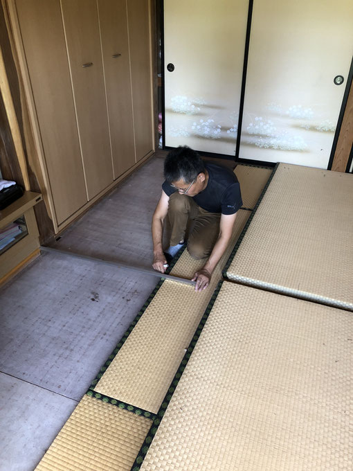 畳職人がスケールを使い、部屋の寸法を正確に採寸している様子。