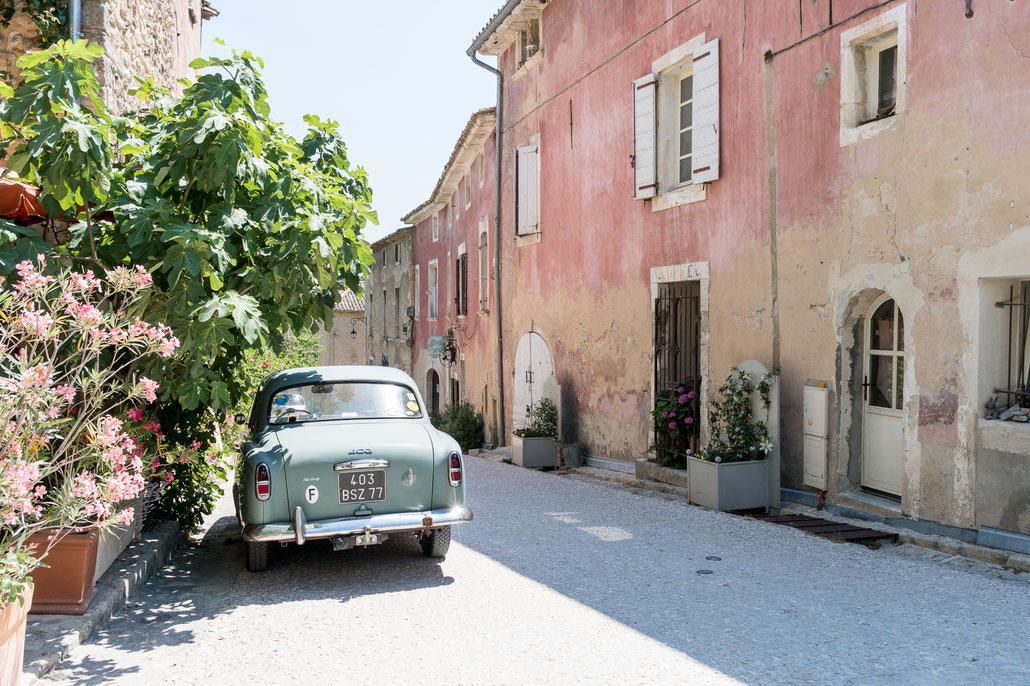 It can't get more provencal then this: A classic french car along with plants and flowers opposite a washed out red wall