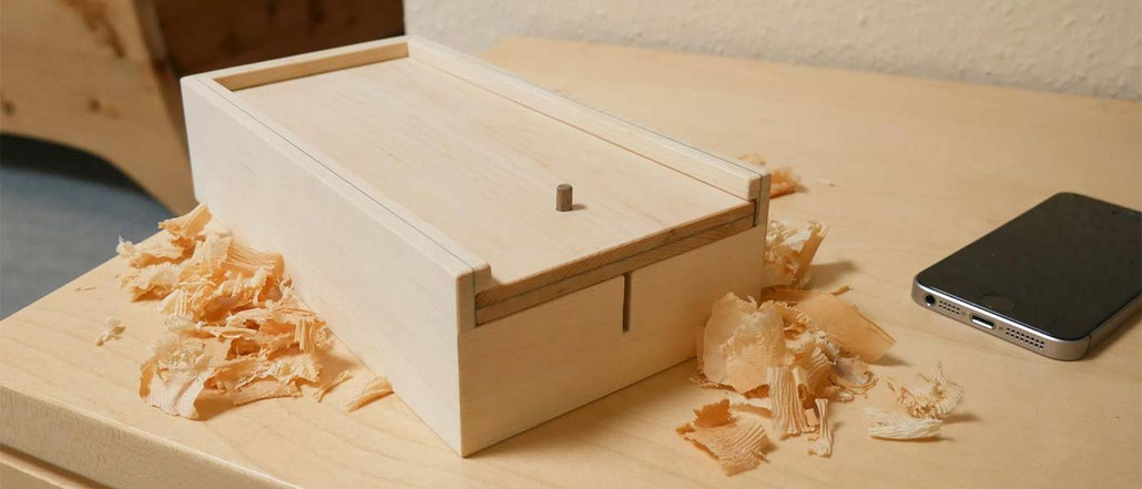 Handybox aus Zirbenholz mit Schiebedeckel zur Abschirmung von Mobilfunkstrahlen, ein Handy liegt daneben